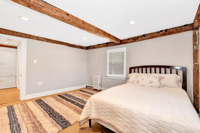 bedroom featuring radiator, baseboards, beam ceiling, and wood finished floors