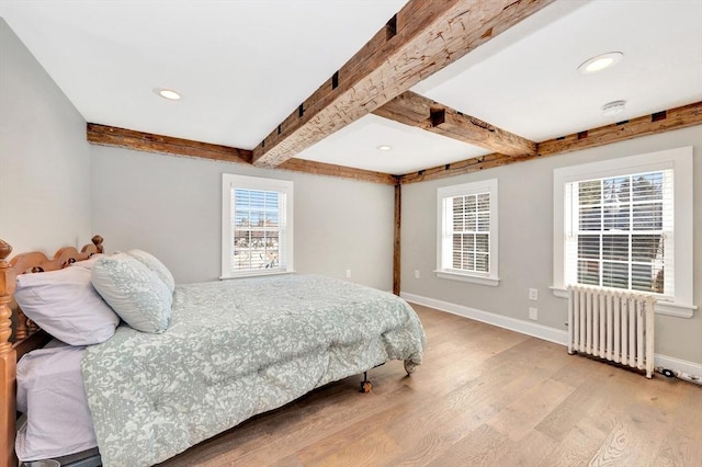 bedroom featuring light wood finished floors, baseboards, radiator, beamed ceiling, and recessed lighting