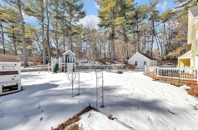 yard layered in snow featuring a playground and a wooden deck