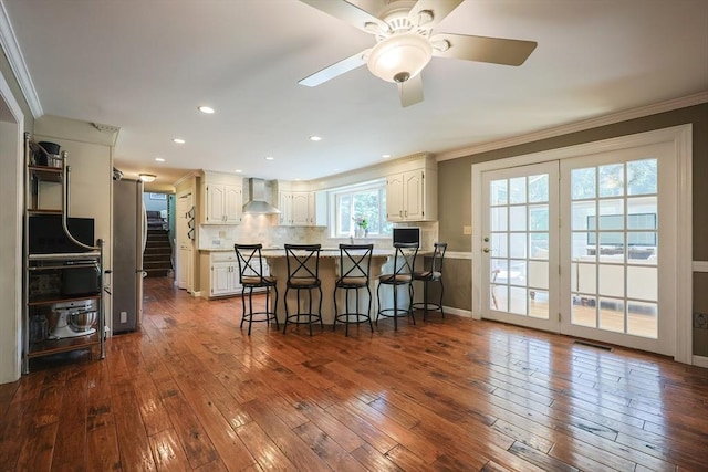 5 Windsor Rd, Lynnfield, MA 01940 - kitchen with wall chimney range hood, ornamental molding, a peninsula, a breakfast bar area, and freestanding refrigerator