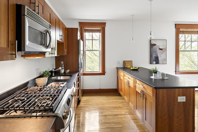 432 Norfolk St Unit 3B, Somerville, MA 02143 - kitchen featuring stainless steel appliances, a peninsula, light wood-style floors, dark countertops, and brown cabinetry