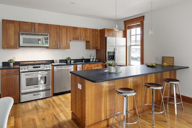 432 Norfolk St Unit 3B, Somerville, MA 02143 - kitchen with stainless steel appliances, dark countertops, brown cabinetry, and light wood-style flooring