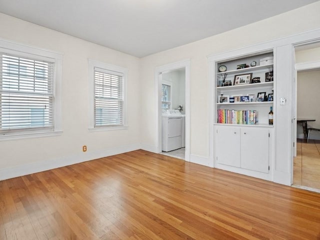 empty room with washer / clothes dryer, light hardwood / wood-style floors, and a healthy amount of sunlight