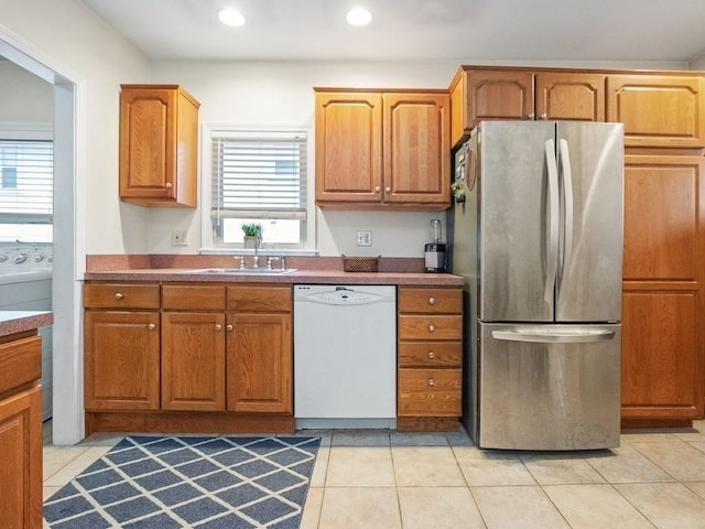 kitchen featuring washer / dryer, sink, light tile patterned floors, stainless steel refrigerator, and dishwasher