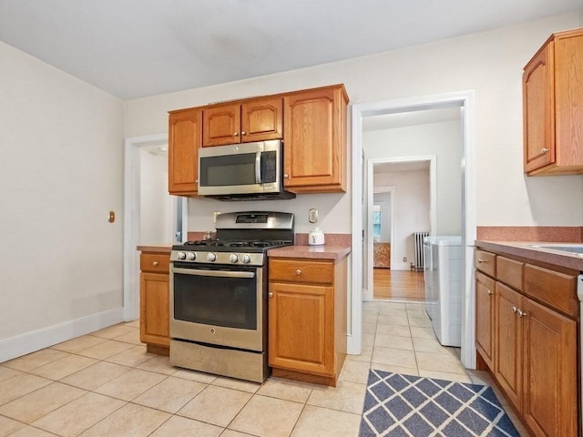 kitchen featuring stainless steel appliances, radiator, and light tile patterned floors