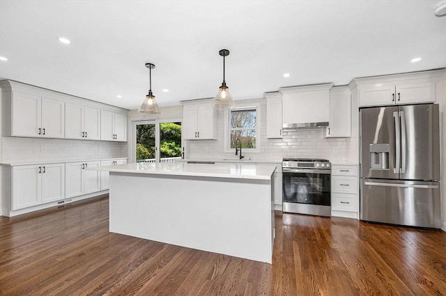 kitchen with appliances with stainless steel finishes, a sink, light countertops, decorative backsplash, and dark wood-type flooring