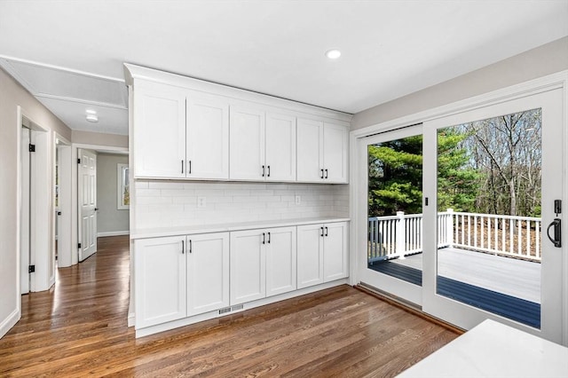 kitchen with white cabinets, backsplash, and wood finished floors