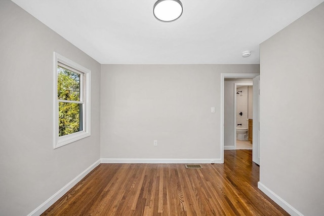 empty room featuring baseboards, wood finished floors, and visible vents
