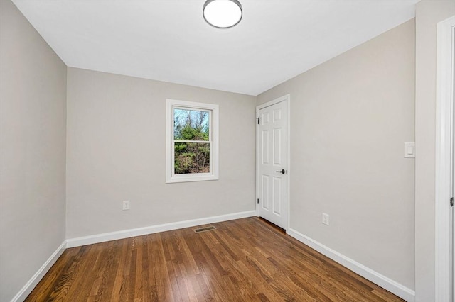 unfurnished room with baseboards, wood finished floors, and visible vents