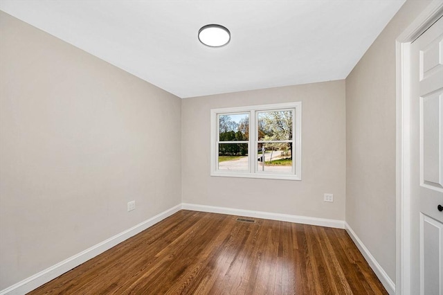 spare room featuring baseboards, wood finished floors, and visible vents