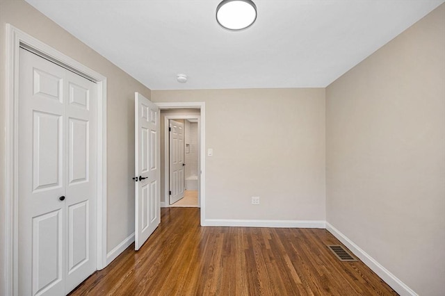 unfurnished bedroom featuring visible vents, baseboards, wood finished floors, and a closet