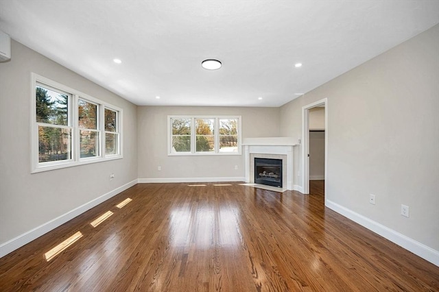 unfurnished living room featuring baseboards, recessed lighting, wood finished floors, and a tile fireplace