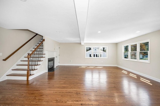 unfurnished living room featuring a fireplace with flush hearth, wood finished floors, stairway, baseboards, and recessed lighting