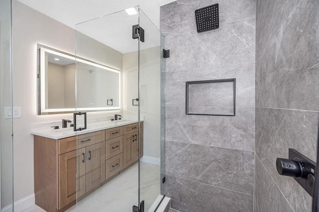 bathroom with a sink, double vanity, marble finish floor, baseboards, and a stall shower