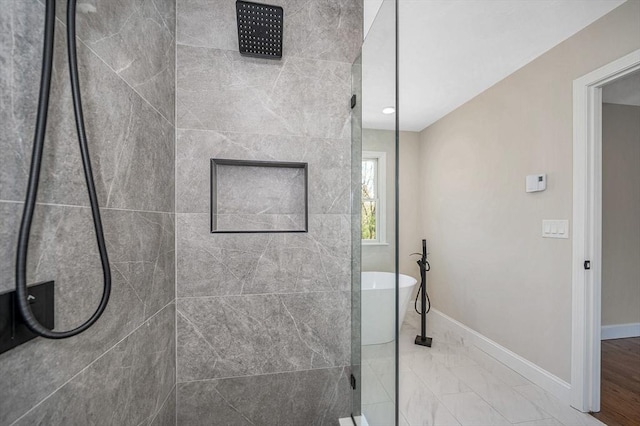 bathroom with a freestanding tub, baseboards, and tiled shower