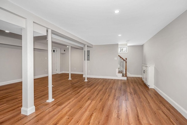 basement featuring recessed lighting, baseboards, stairway, and light wood-style floors