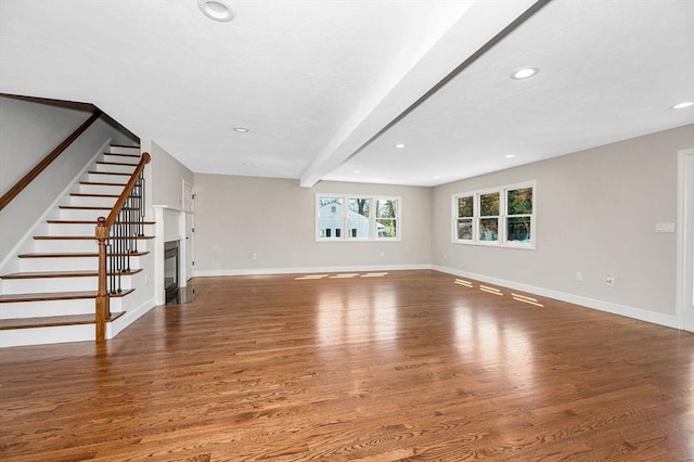 unfurnished living room with baseboards, a fireplace with flush hearth, wood finished floors, and stairway