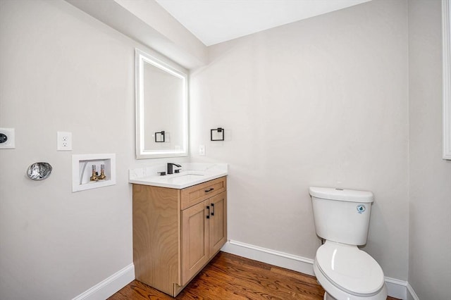 half bath featuring toilet, baseboards, wood finished floors, and vanity