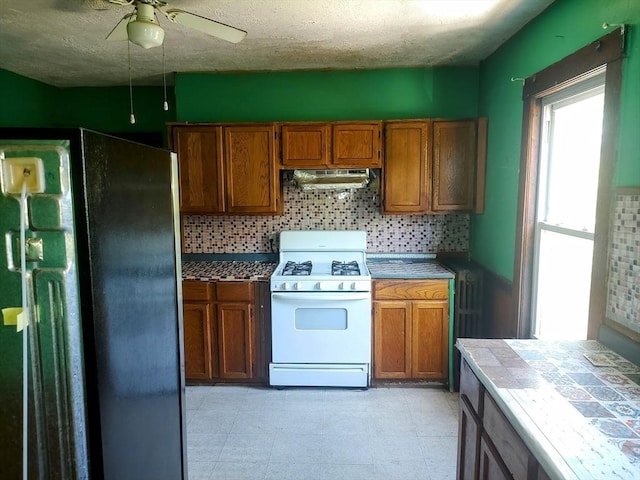 61-63 Grant St, Somerville, MA 02145 - kitchen with white gas stove, freestanding refrigerator, decorative backsplash, extractor fan, and a textured ceiling