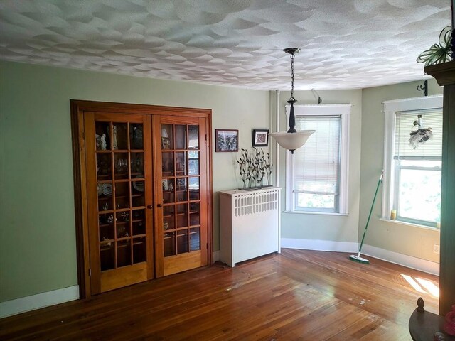 61-63 Grant St, Somerville, MA 02145 - dining room featuring radiator, a textured ceiling, baseboards, and wood finished floors