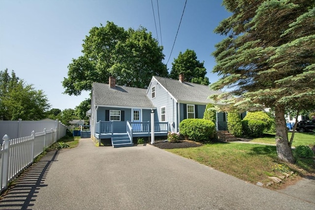 12 Beverly Cir, Randolph, MA 02368 - view of front of home featuring asphalt driveway, a chimney, a deck, and roof with shingles