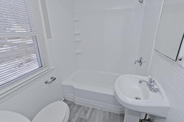 full bathroom with sink, shower / tub combination, tile walls, wood-type flooring, and toilet