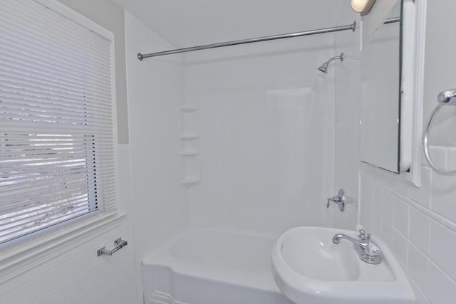 bathroom featuring sink, tile walls, and bathtub / shower combination