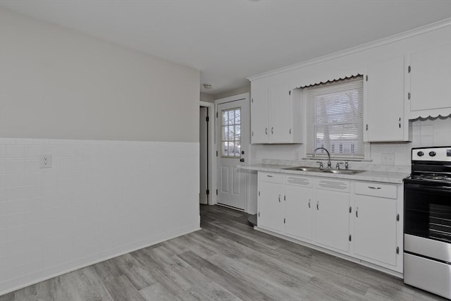 kitchen with sink, white cabinetry, stainless steel range with electric stovetop, tile walls, and light wood-type flooring