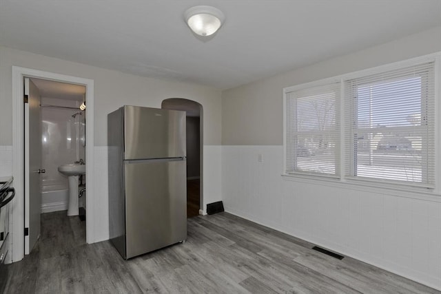 interior space with sink, stainless steel fridge, light hardwood / wood-style floors, and range