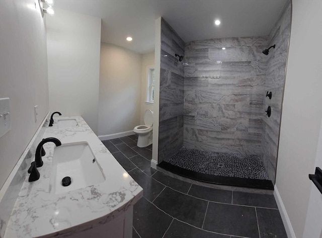 bathroom with tiled shower, vanity, toilet, and tile patterned flooring