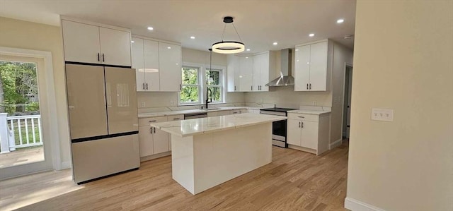 kitchen featuring electric stove, wall chimney range hood, fridge, a center island, and decorative light fixtures