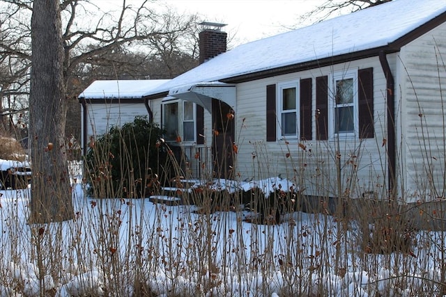 snow covered property with a chimney