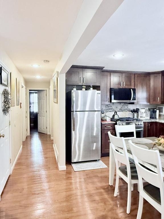 kitchen with appliances with stainless steel finishes, light wood-type flooring, light countertops, and dark brown cabinets