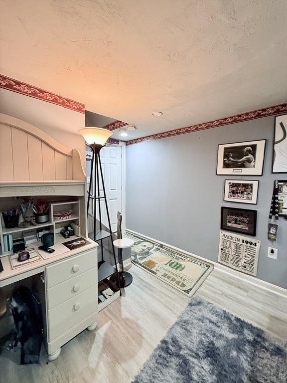 office featuring a textured ceiling, light wood finished floors, and baseboards