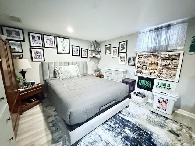 bedroom with baseboards, visible vents, and wood finished floors