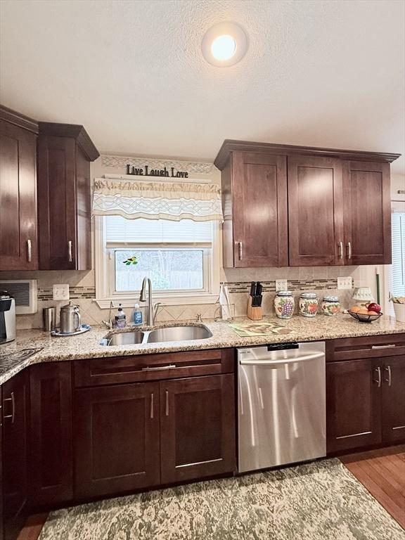 kitchen with dark brown cabinetry, tasteful backsplash, light wood finished floors, dishwasher, and a sink