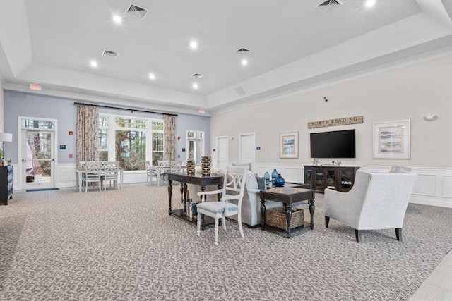 living room with a raised ceiling and light colored carpet