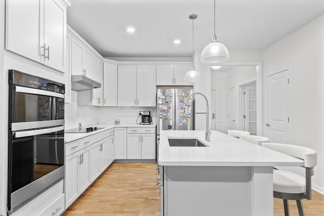 kitchen featuring light wood-type flooring, white cabinetry, and a kitchen island with sink