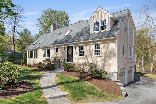 new england style home featuring a chimney, a garage, asphalt driveway, roof with shingles, and a front lawn