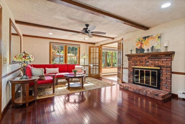 living area with a baseboard radiator, beam ceiling, hardwood / wood-style flooring, a textured ceiling, and ceiling fan
