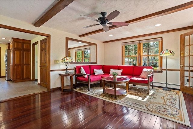living area with beamed ceiling, healthy amount of natural light, a baseboard radiator, baseboards, and hardwood / wood-style flooring