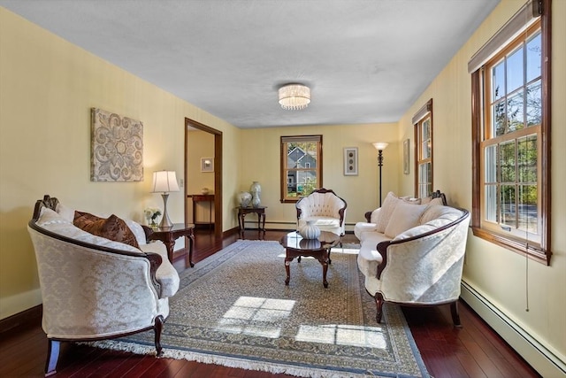 living room with a baseboard heating unit, hardwood / wood-style flooring, baseboards, and plenty of natural light