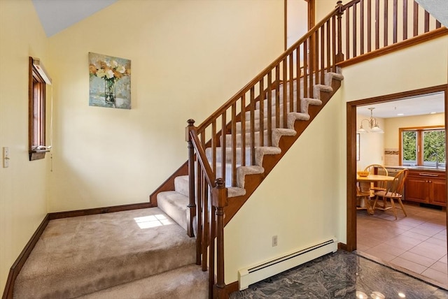 stairway featuring a baseboard heating unit, high vaulted ceiling, and baseboards