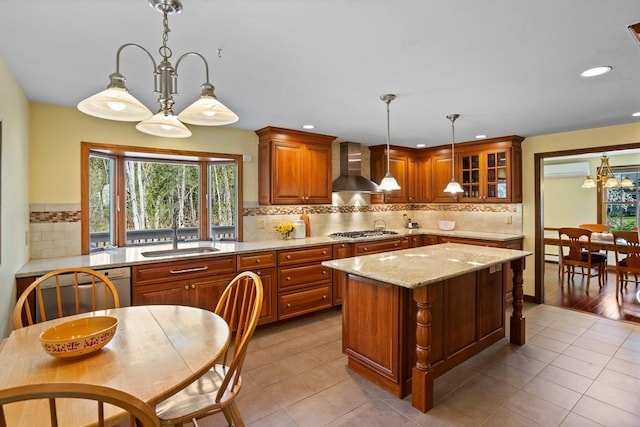 kitchen featuring wall chimney exhaust hood, a sink, stainless steel gas stovetop, decorative backsplash, and light stone countertops