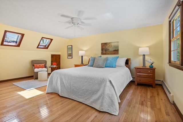 bedroom featuring baseboard heating, a skylight, wood-type flooring, baseboards, and ceiling fan