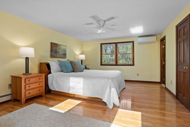 bedroom featuring a wall mounted AC, light wood-type flooring, baseboards, and ceiling fan