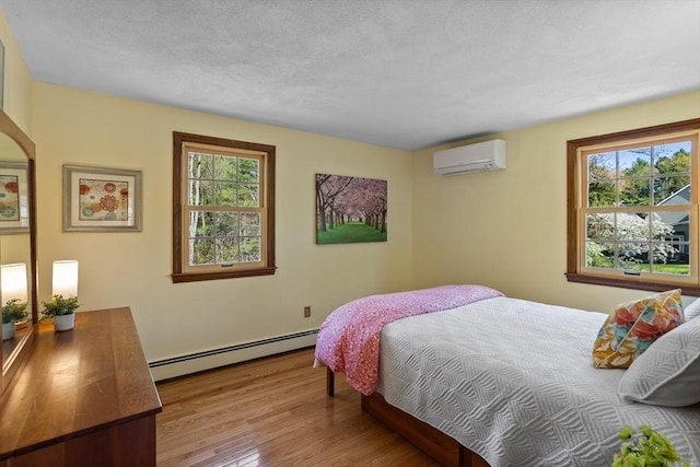 bedroom with a baseboard radiator, an AC wall unit, multiple windows, wood finished floors, and a textured ceiling
