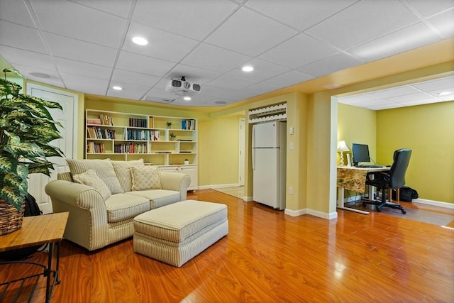 living room featuring a drop ceiling, baseboards, a desk, wood finished floors, and recessed lighting