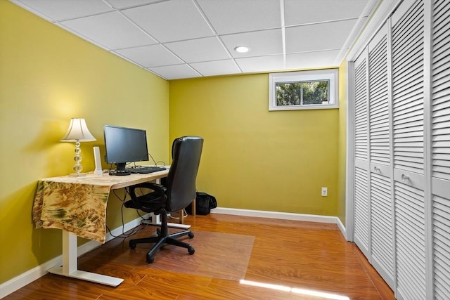 office featuring a drop ceiling, baseboards, wood finished floors, and recessed lighting