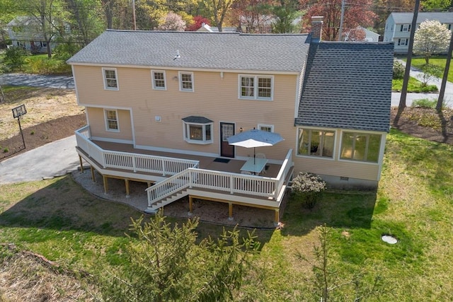 rear view of house with a shingled roof, a wooden deck, a lawn, and crawl space